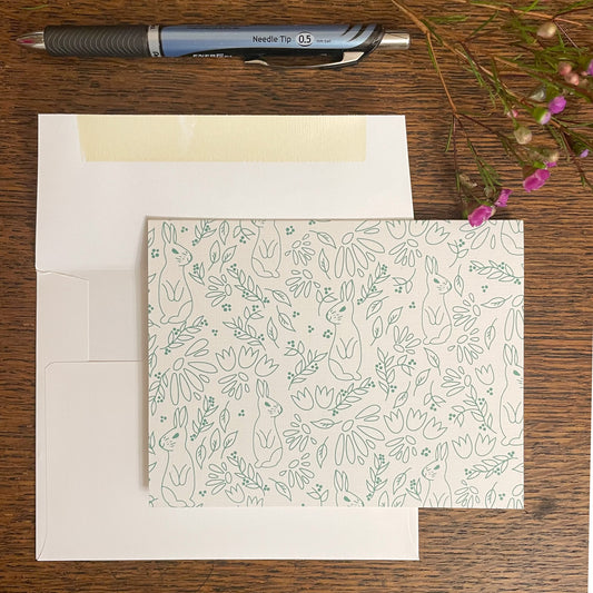Photo of card with envelope and pen next to flowers.