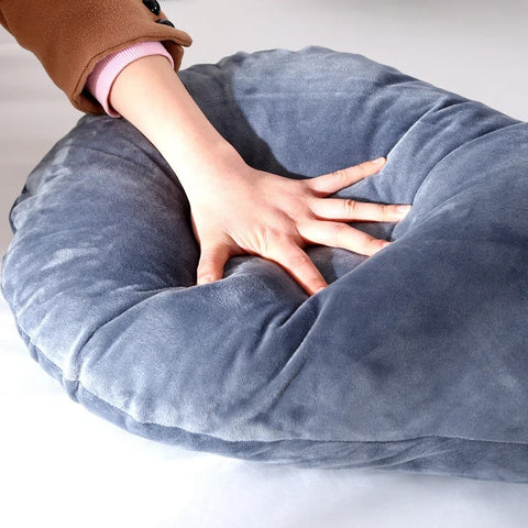 Une main tâtant le coussin d'allaitement gris