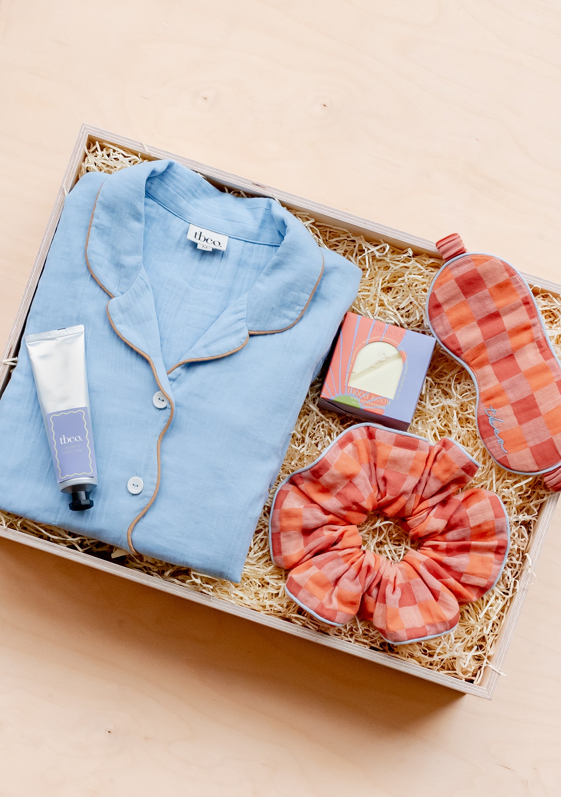 Flat lay of gift box with blush lambswool scarf and add-ons