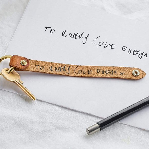 A leather keyring printed with the message "To Daddy Love Evelyn" in a child's handwriting