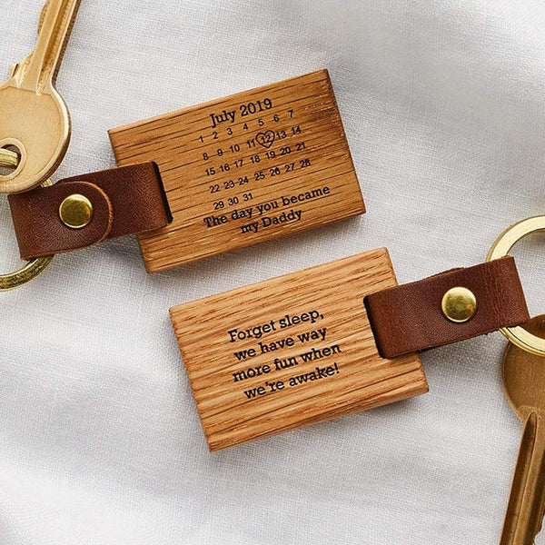 A wooden keyring engraved with a calendar. A date is circled on the calendar and the inscription beneath reads 'the day you became my daddy'. On the reverse of the keyring is the message 'forget sleep, we have way more fun when we're awake!'