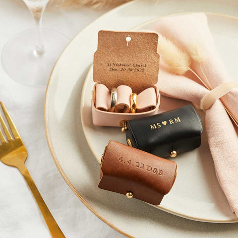 Three leather wedding ring pouches with personalised initials in gold foil - the wedding ring pouches are shown in black, tan brown and blush pink leather