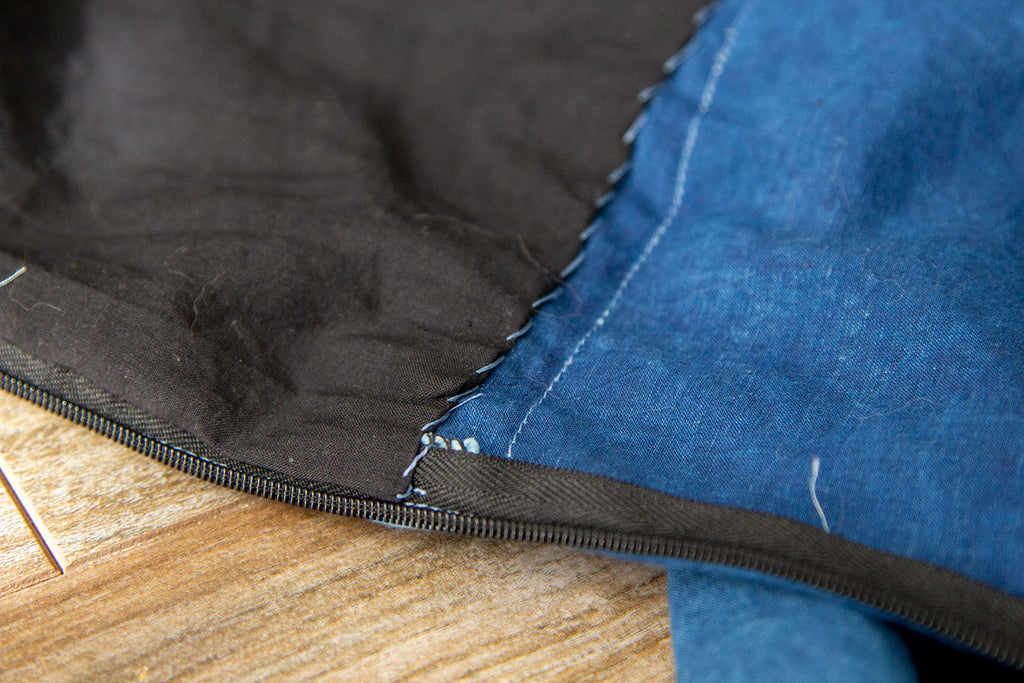 A close up of the hand sewn lining at the CB edge near the invisible zipper. There are visible whip stitches where the lining was delicately attached to the inner jumpsuit