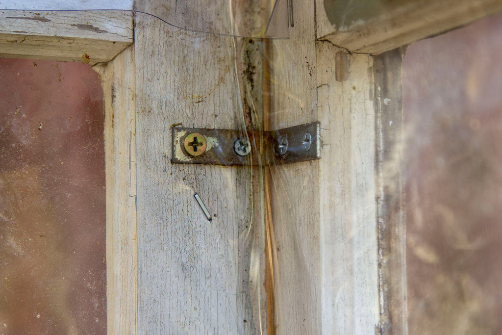 Close up of a black mini-l bracket holding together two sides of the greenhouse walls