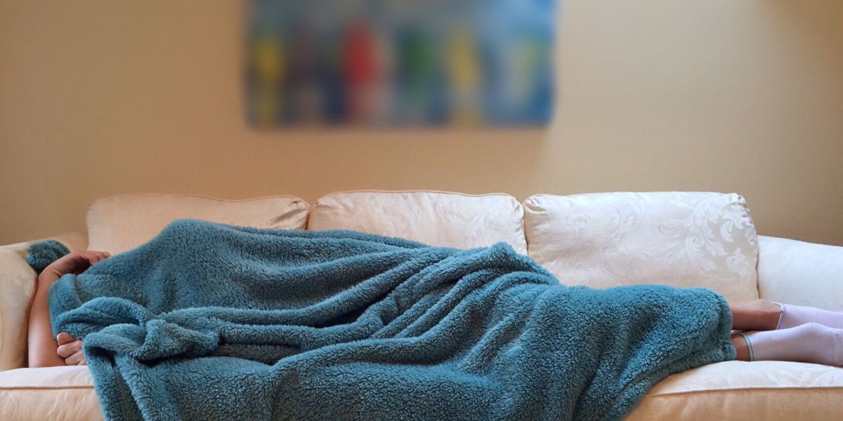 person covered with blanket on a couch