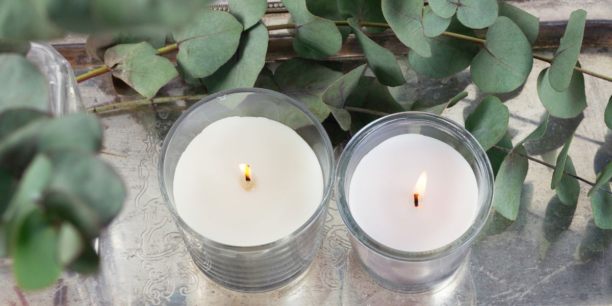 two small candles surrounded by greenery