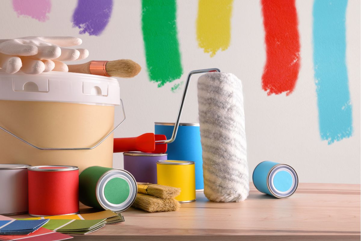 a paint roller near colorful paint stripes on the wall