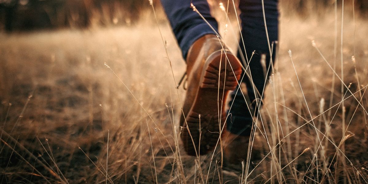 the feet of someone walking through a field
