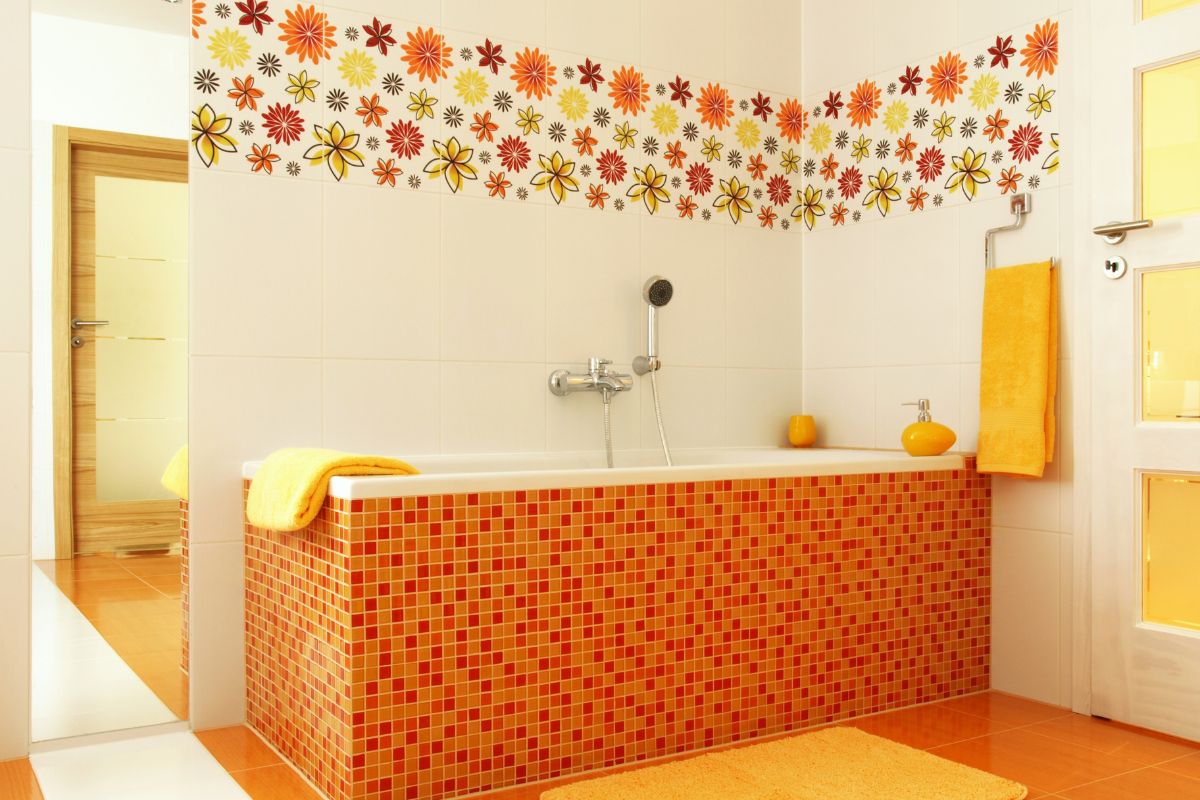 an orange bathroom with a big tiled tub and whimsical wall decals