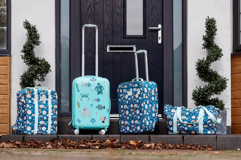 image shows the little luggage range of kids and baby luggage outside a house,  a suitcase, tote bag and backpack