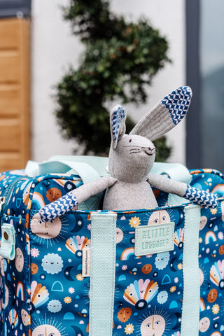 image shows the little luggage co folding backpack outside with a soft toy bunny sat in pocket