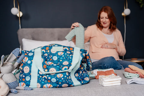 image shows young pregnant woman packing a hospital bag using the little luggage co tote bag