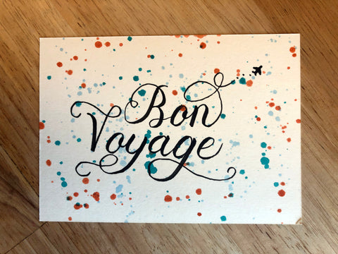 A greeting card that says "Bon Voyage" with splatter paint details