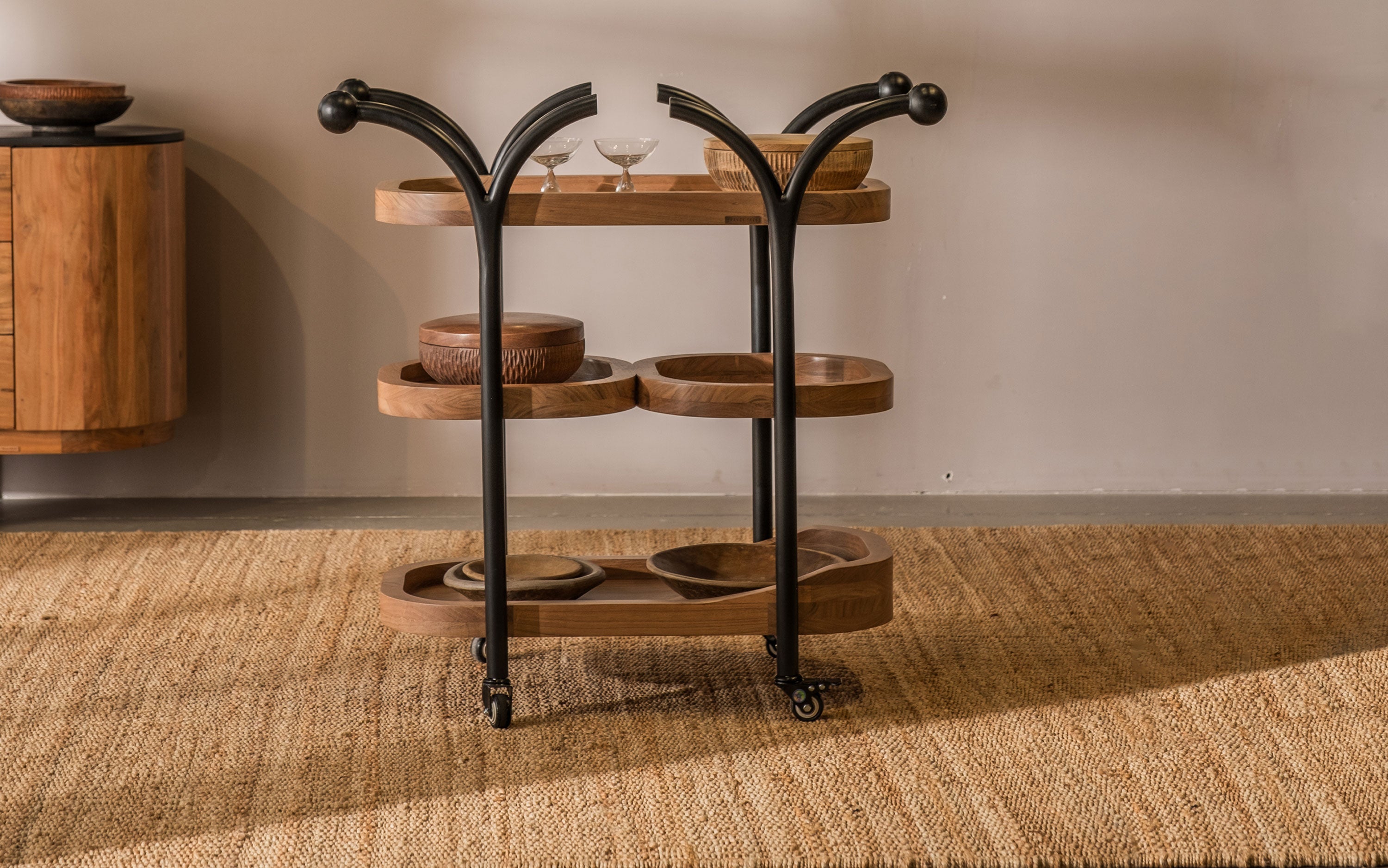 A natural wooden service trolley with multiple shelves and wheels, ideal for use in home bar settings