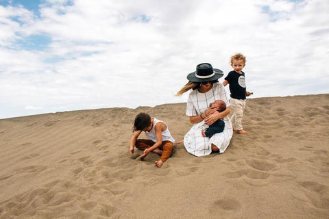 A mother on the beach wearing the Grid Dress by Piper & Scoot