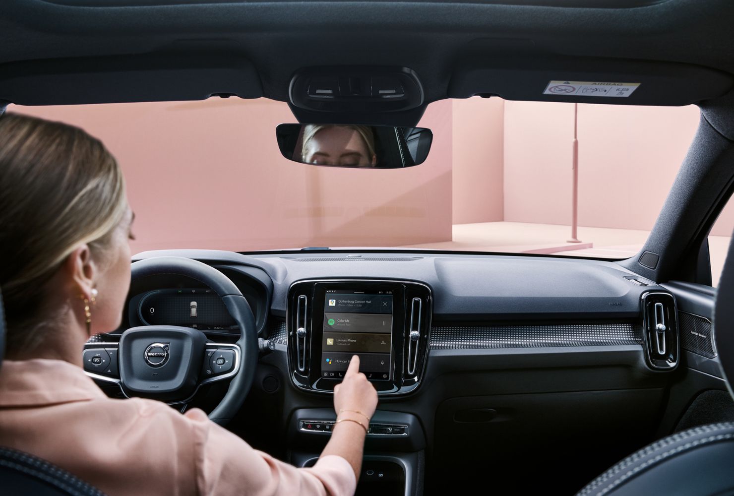 A model in a Volvo car using the menu on the screen in front of her.