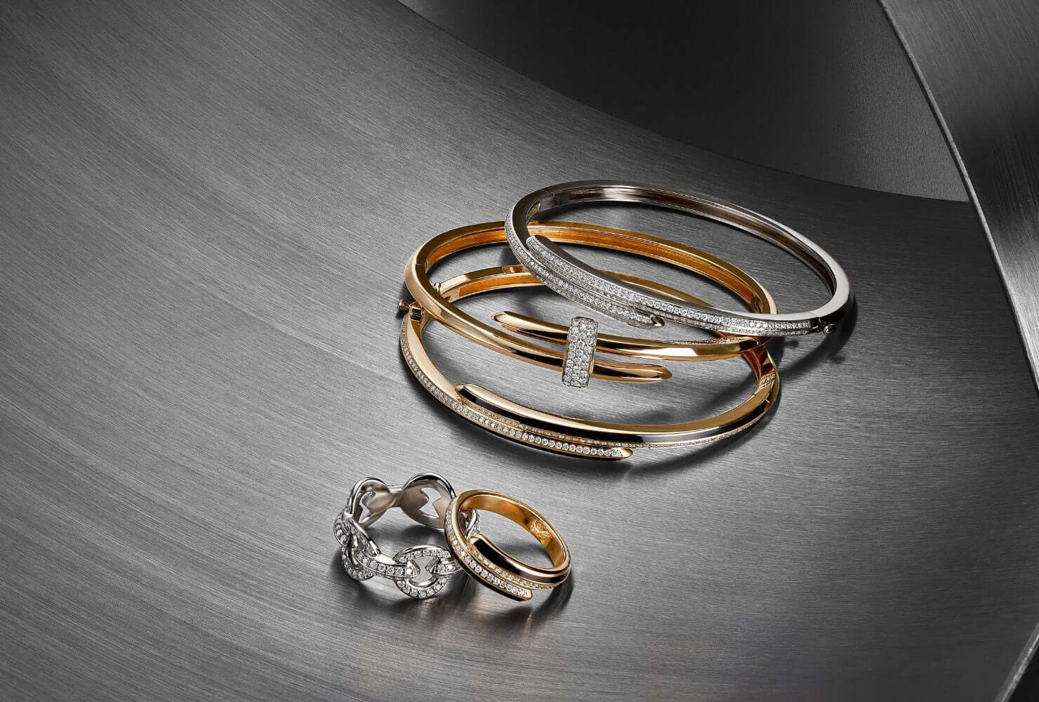 Image of three Duel bracelets next to two Duel rings on a grey work surface.