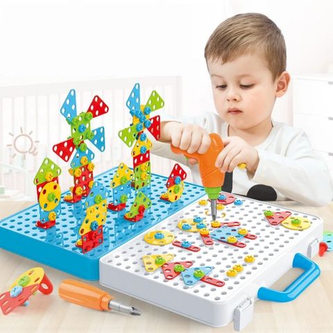 Enfant concentré utilisant une visseuse électrique pour enfant sur un jeu de construction coloré, développant sa motricité fine