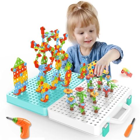 Une enfant joue avec un jeu de construction coloré, assemblant des pièces sur une plaque de base. À côté d'elle, une visseuse électrique pour enfant en plastique ABS, conçue pour la sécurité des jeunes utilisateurs, souligne l'aspect interactif du jeu