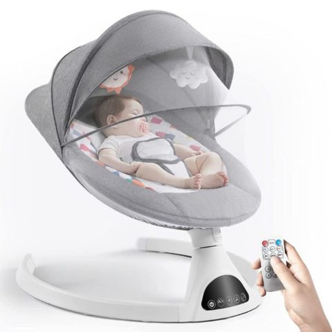 Un bébé dormant dans la balancelle bébé électrique avec une main en bas de l'image activant une télécommande