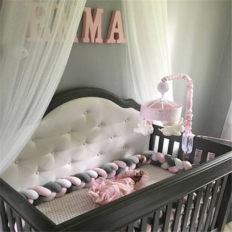 Un berceau dans une chambre avec une tresse de lit bébé blanc-gris-rose