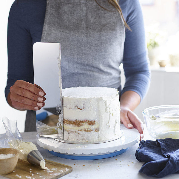 Using a metal side scraper to crumb coat your cake