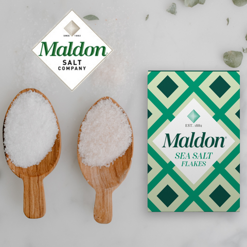 Maldon Salt next to two wooden spoons with coarse salt in the spoons