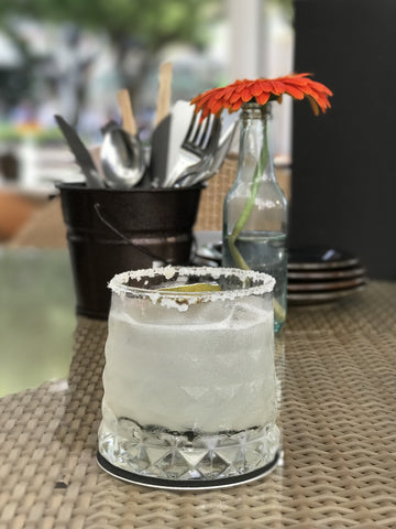 Tumbler on a restaurant table filled with margarita. The rim is rolled in salt.