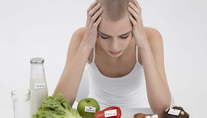 young-woman-with-an-eating-disorder-next-to-food-with-calories-numbers