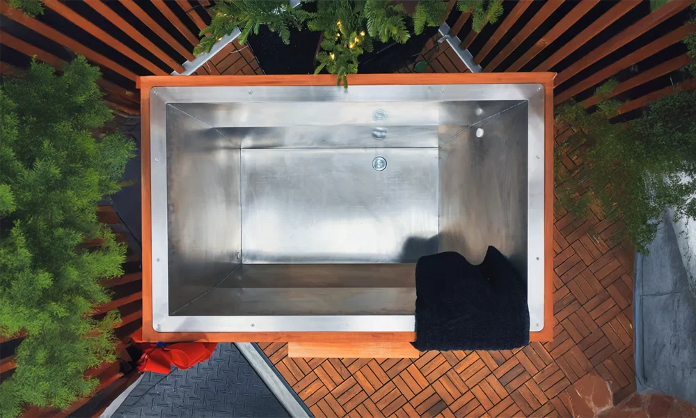high end stainless steel cold plunge tub with black exterior and wooden trim