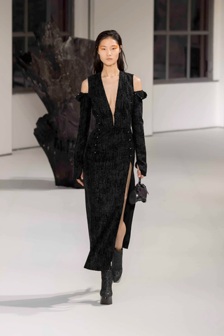 Model in all-black look with a plunging neckline, leg slit, and cold shoulder cut