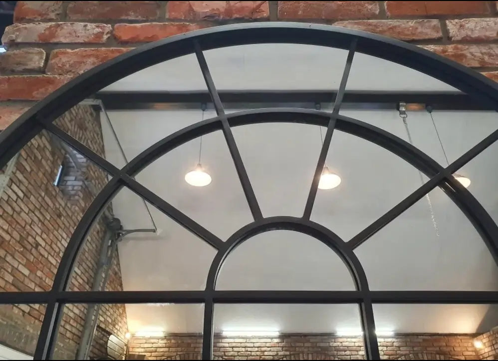 Detail view of large arched dungeon mirror with steel frame, perfect for enhancing sex dungeon depth and visibility