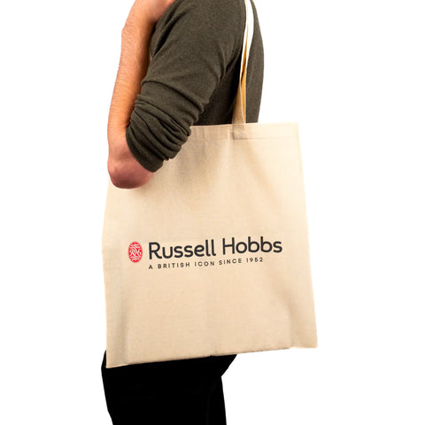 A man walking with a natural cotton tote bag printed with Russell Hobs Logo on the side of the bag