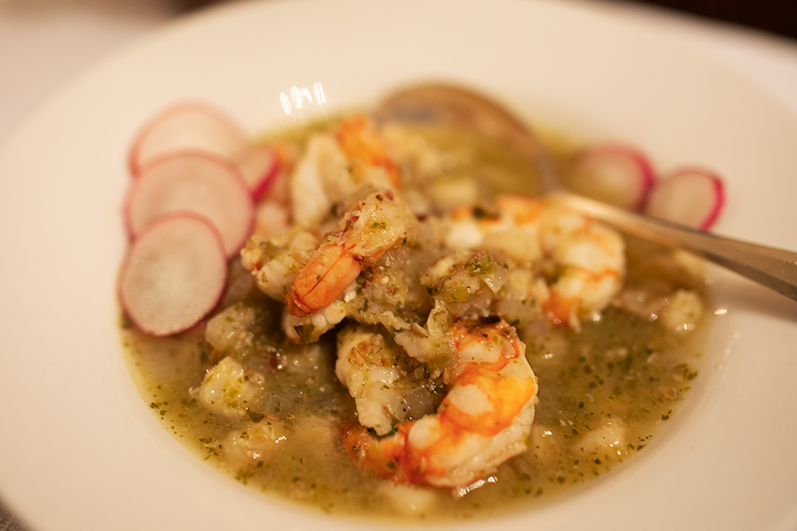 Green shrimp pozole in a serving bowl, garnished with fresh radishes