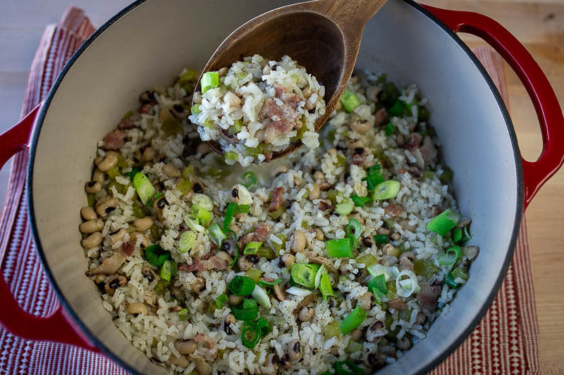 Dutch oven with cooked rice and black eyed peas, topped with green onions