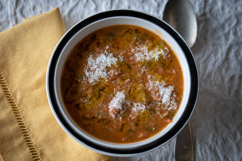 Bowl of bean, bread, and vegetable stew garnished with Parmesan cheese