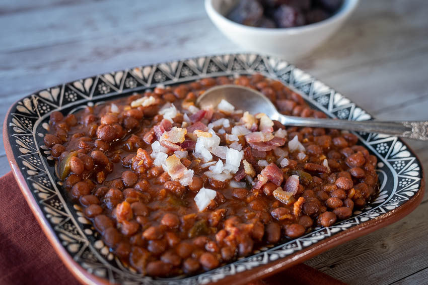 Rancho Gordo Santa Maria Pinquito beans cooked with dates and spices, topped with fresh onion