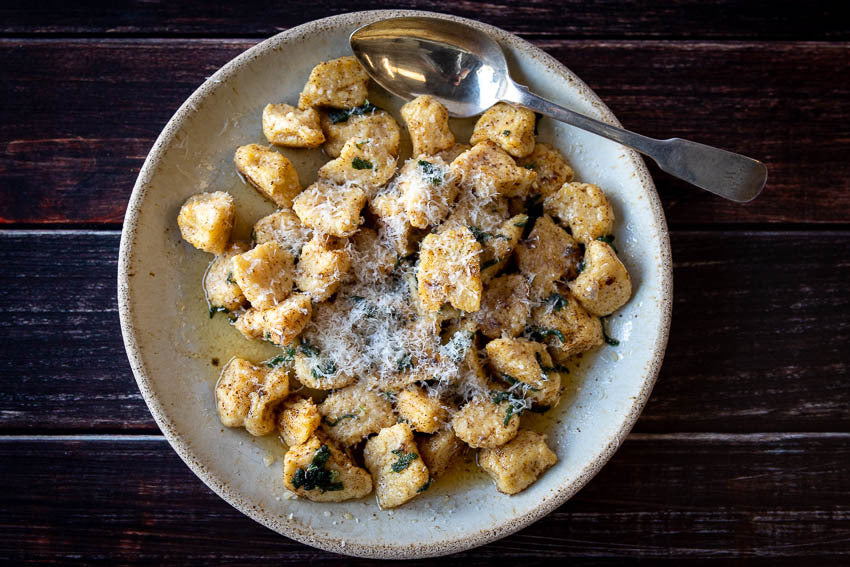 Polenta gnocchi in a shallow serving bowl, dusted with Parmesan