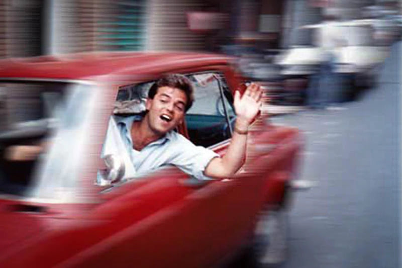 Man in red car waving