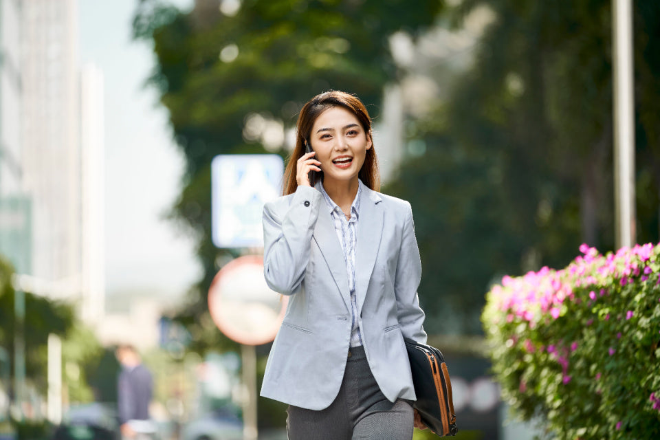 Asian woman walking outside while talking on the phone