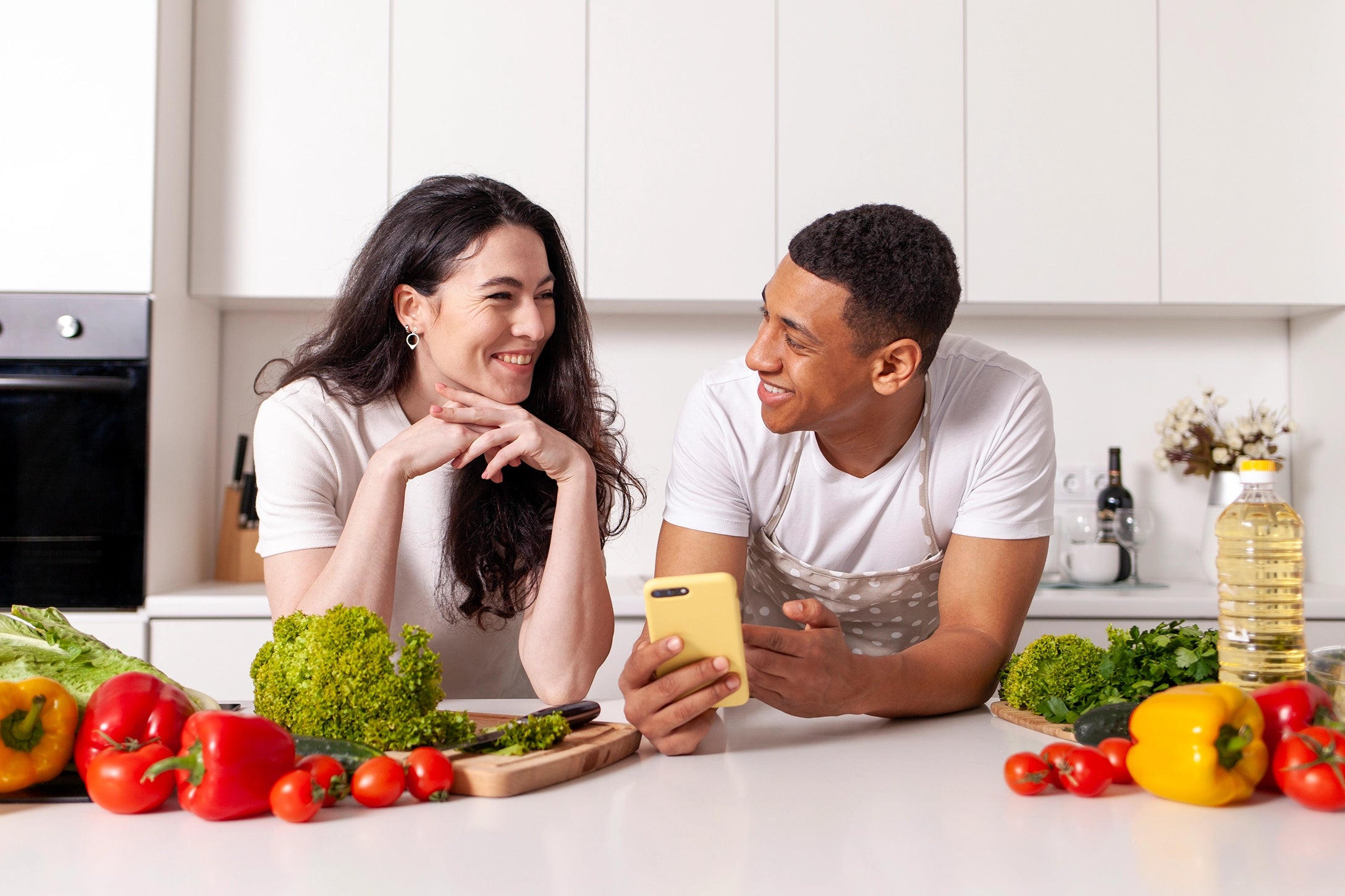 Casal na cozinha, cercados de alimentos saudáveis e veganos.