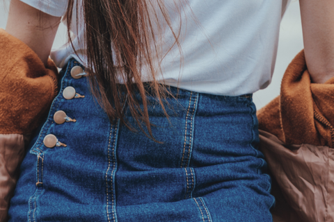 Photo d'une femme portant une jupe en jean avec un t-shirt et une veste blancs.