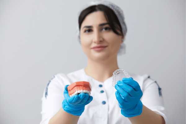   Dentist Presenting a Jaw Model with Wire Braces and Aligners for Comparison