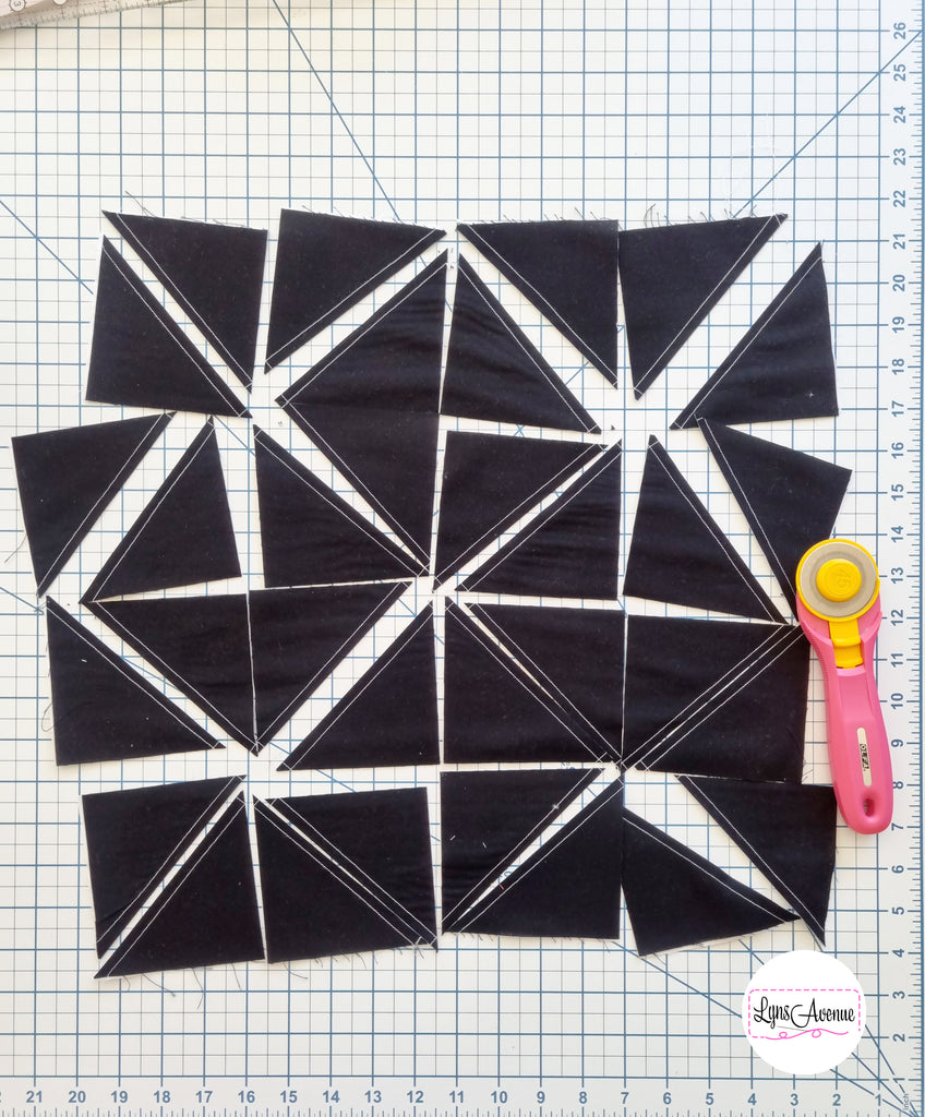 Photo showing 32 black half square triangles untrimmed and not pressed.