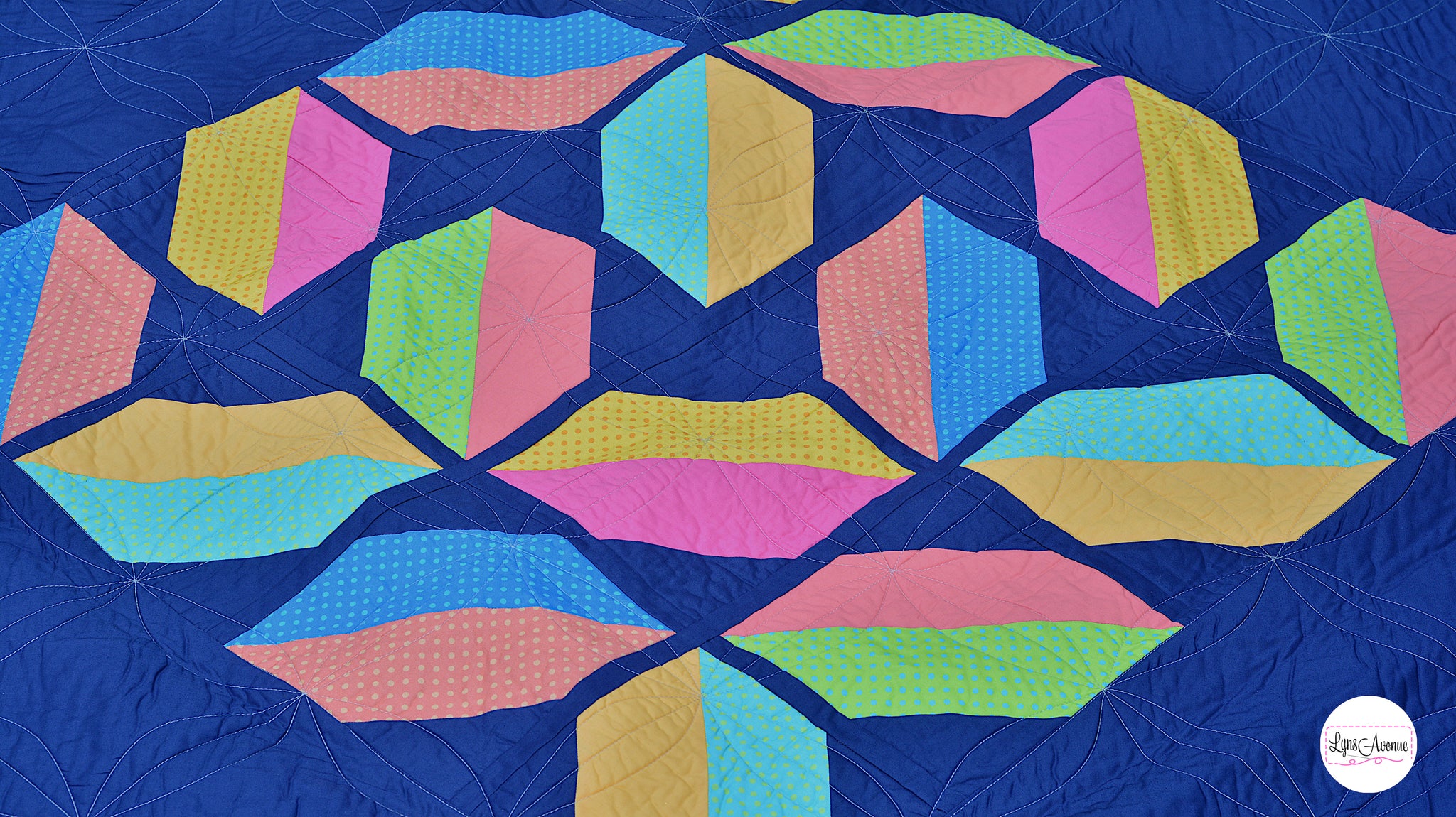 Flourishing Quilt pattern - a flower design quilt pattern in bright pink, yellow, blue and peach colour on a navy blue background