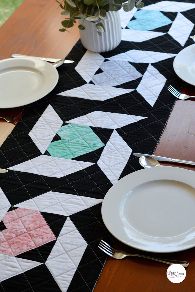 Image showing a table runner in black white, pink and green colours on a brown table background