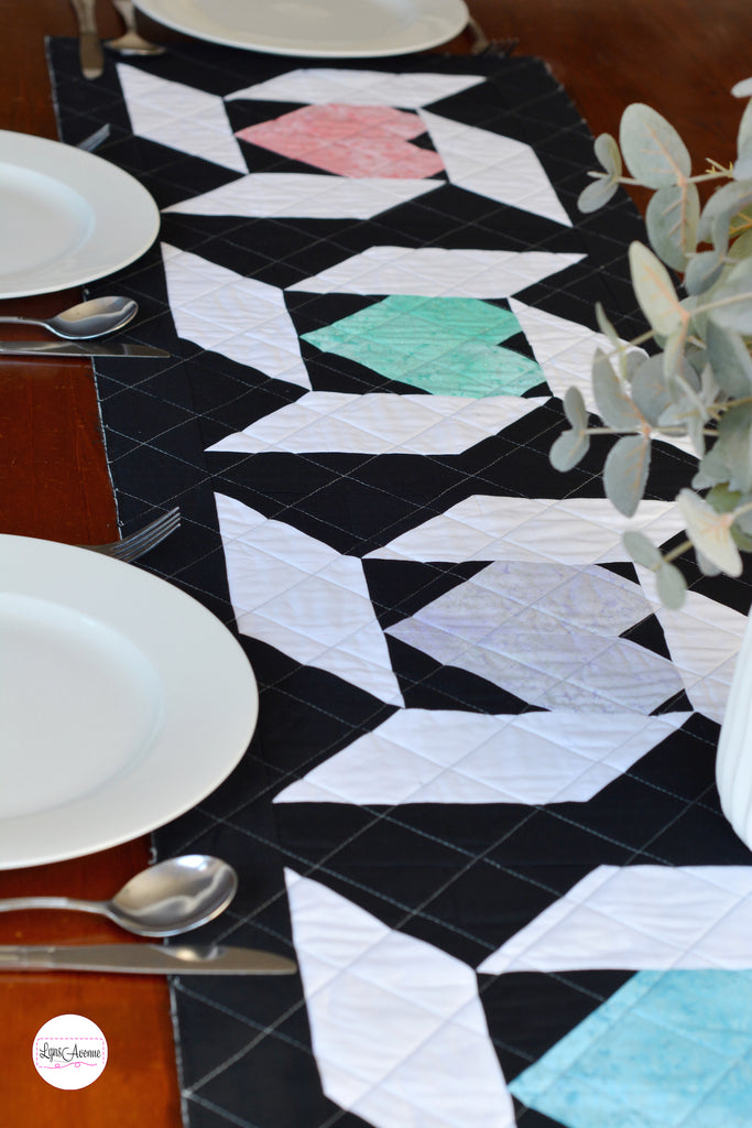 Image showing a table runner in black white, pink, purple and green colours on a brown table background