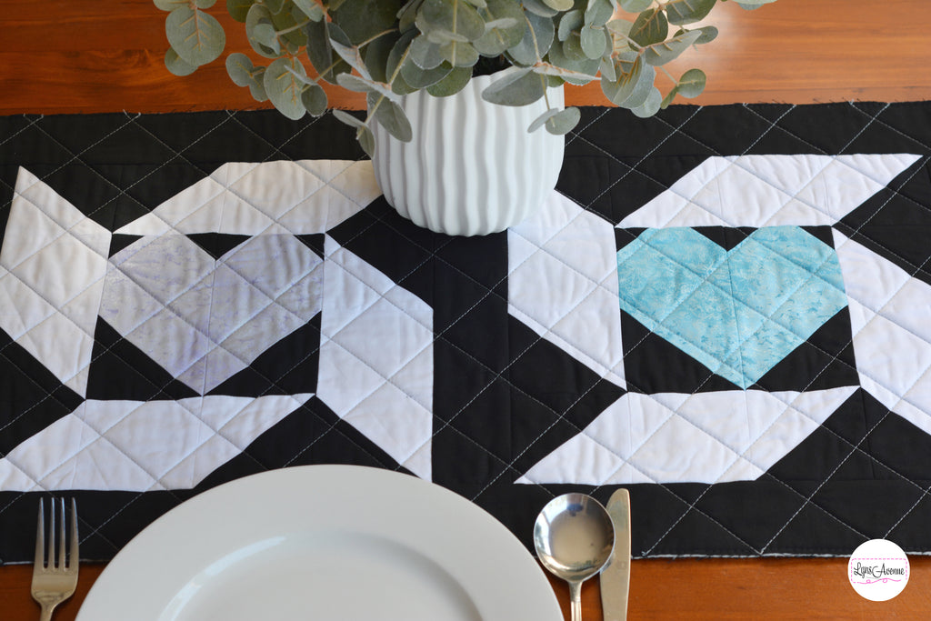 Image showing a table runner in black white, purple and green colours on a brown table background