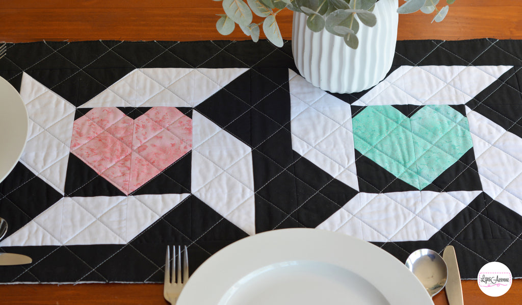 Image showing a table runner in black white, pink and green colours on a brown table background