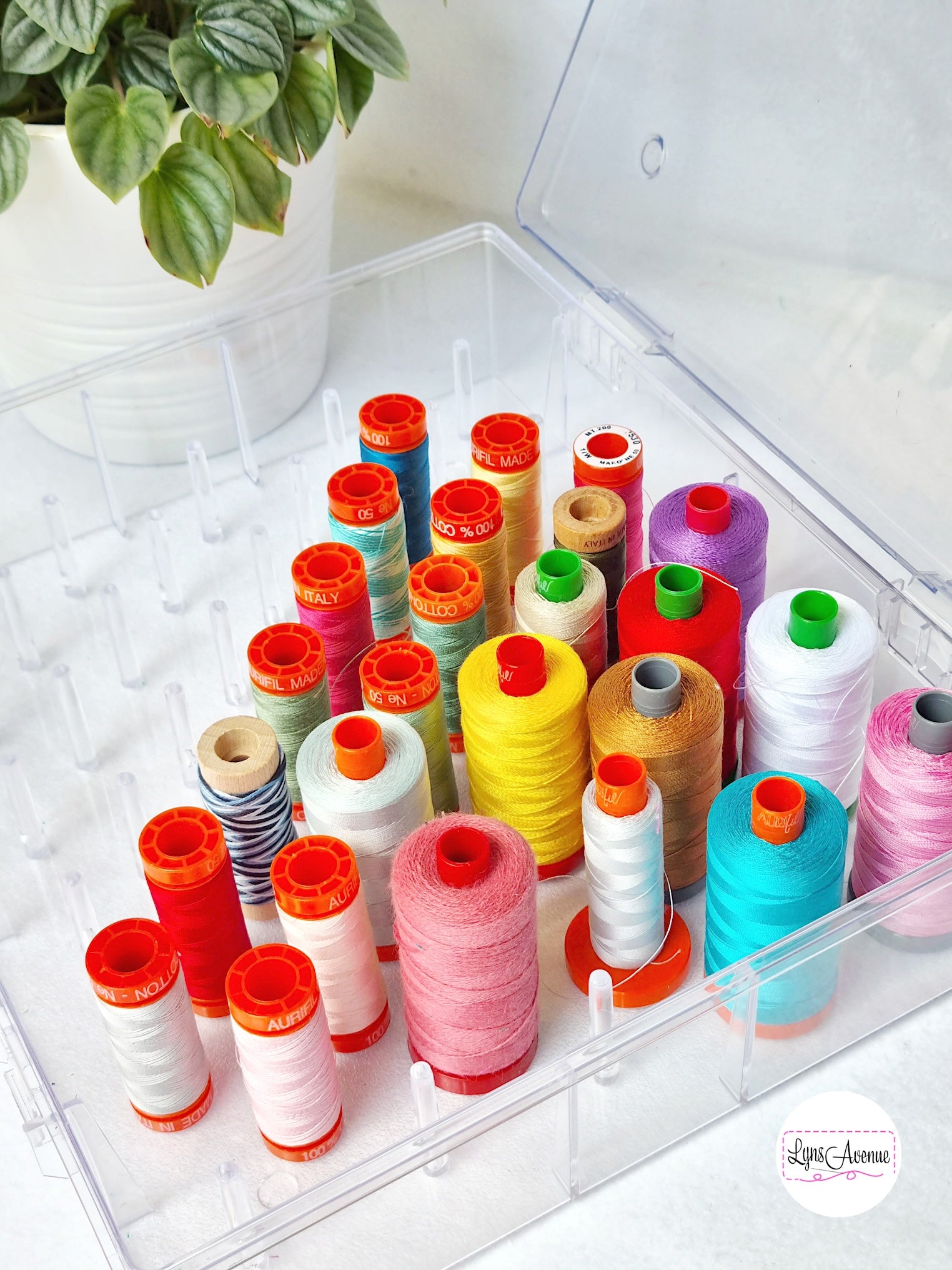 different coloured Aurifil threads in a plastic storage container with spools